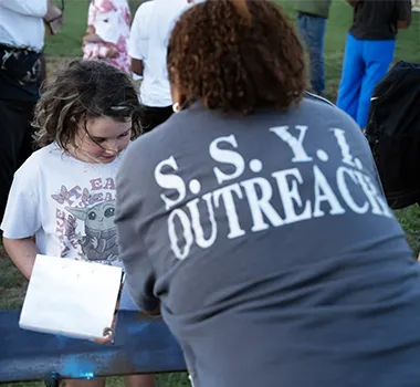 Outreach worker assisting child at outdoor event